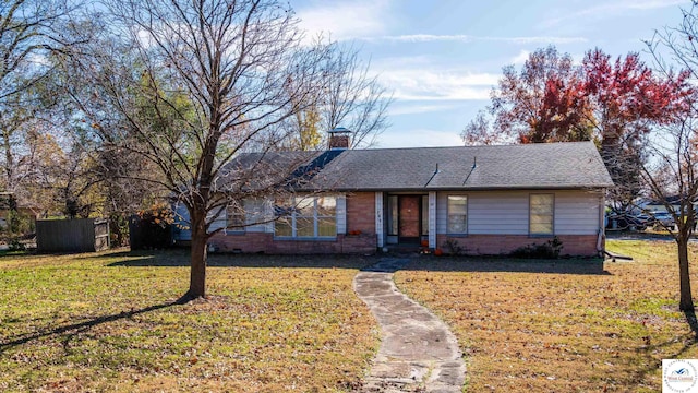 view of front facade with brick siding, roof with shingles, a chimney, and a front yard