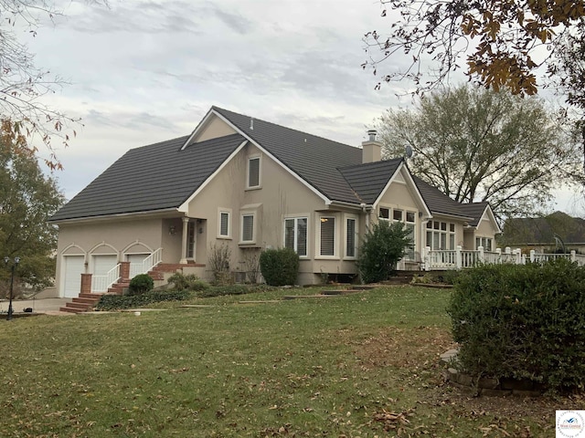 view of front of home with an attached garage, a chimney, a front lawn, and stucco siding