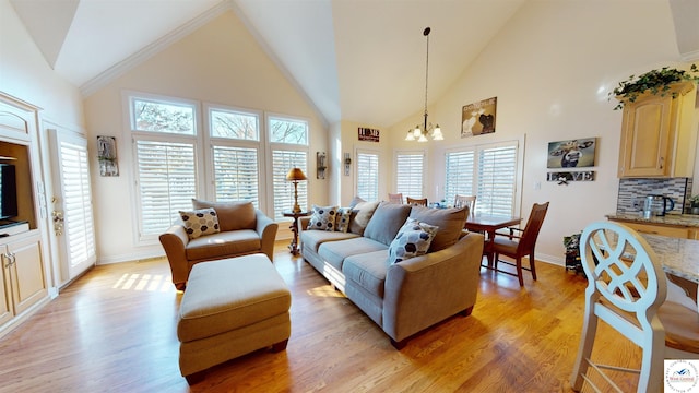 living room with a chandelier, baseboards, high vaulted ceiling, and light wood finished floors