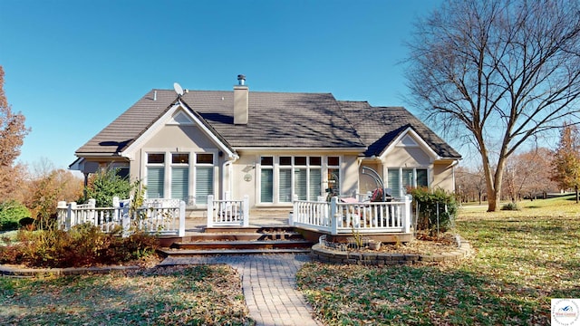 rear view of house featuring a yard, a chimney, a wooden deck, and stucco siding