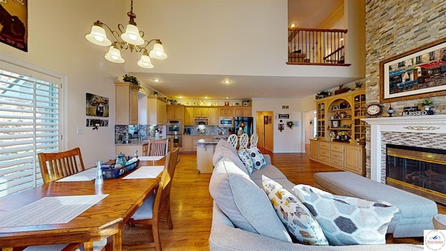 interior space featuring a chandelier, a high ceiling, a tiled fireplace, and light wood-style floors