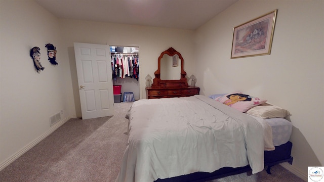 carpeted bedroom featuring a closet, a walk in closet, visible vents, and baseboards