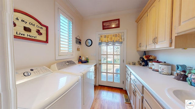 laundry room with ornamental molding, a healthy amount of sunlight, cabinet space, and washer and dryer