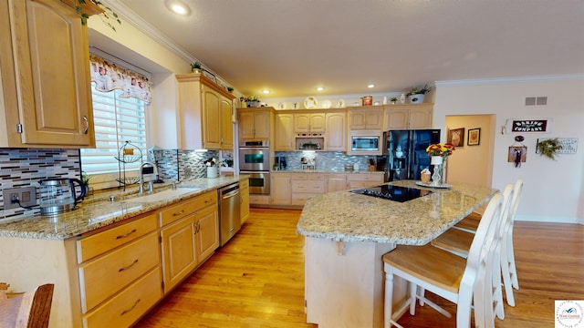 kitchen with visible vents, a center island, black appliances, a kitchen bar, and a sink