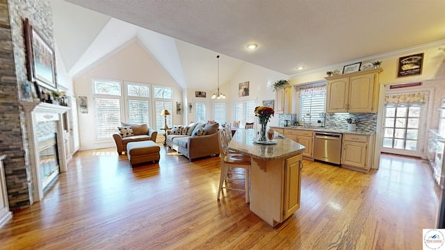 kitchen with a glass covered fireplace, a breakfast bar area, open floor plan, a center island, and stainless steel dishwasher