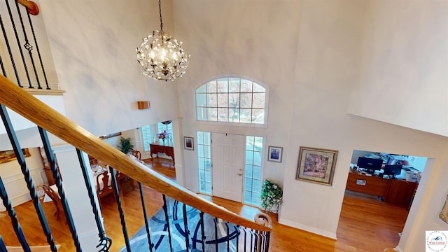 entrance foyer with a chandelier, a high ceiling, wood finished floors, baseboards, and stairway