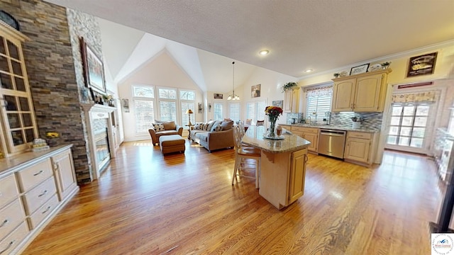 kitchen with a kitchen island, a breakfast bar area, open floor plan, a fireplace, and stainless steel dishwasher