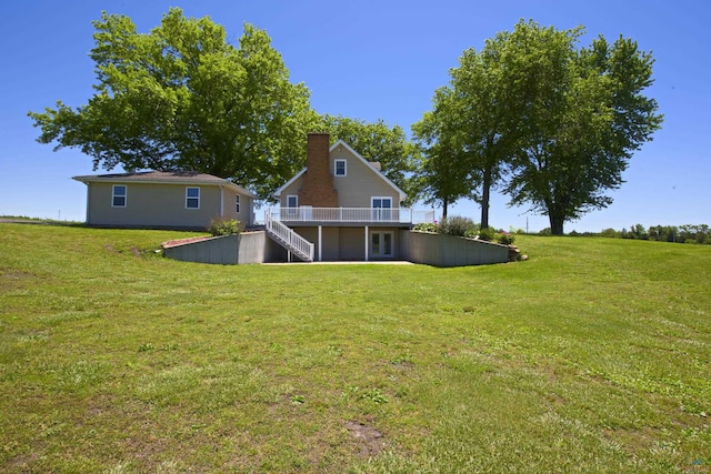 rear view of property featuring a wooden deck, a chimney, stairway, and a yard