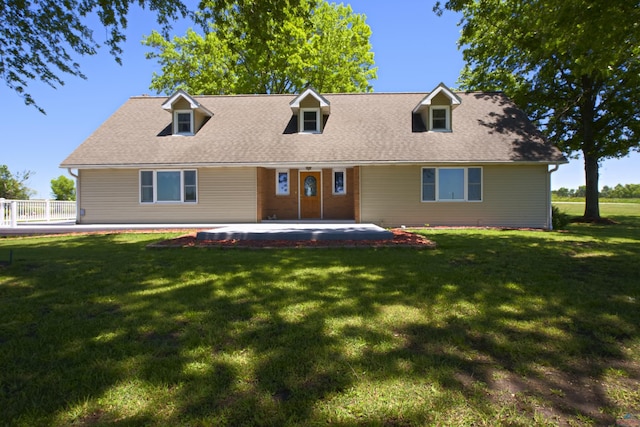 view of front of property with a patio area, roof with shingles, and a front yard