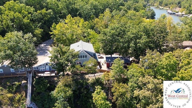 birds eye view of property featuring a water view and a wooded view