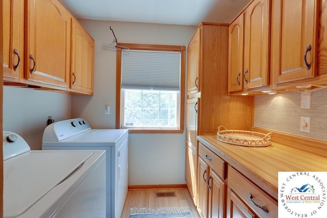 washroom with light wood finished floors, cabinet space, visible vents, washing machine and dryer, and baseboards