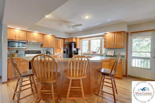 kitchen featuring light countertops, a center island, stainless steel microwave, and black refrigerator with ice dispenser