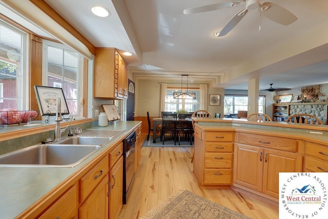 kitchen featuring black dishwasher, pendant lighting, light countertops, light wood-style flooring, and a sink