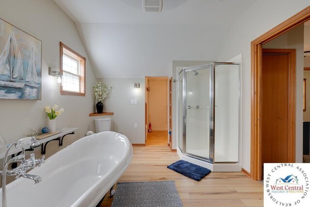 bathroom featuring a stall shower, visible vents, vaulted ceiling, and wood finished floors