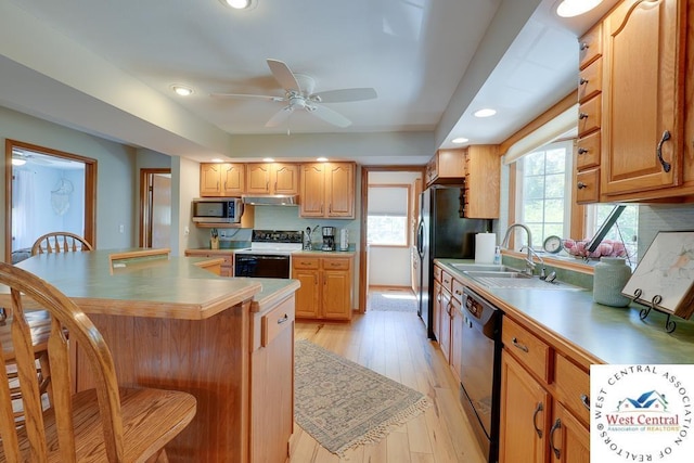 kitchen featuring a breakfast bar, black dishwasher, light countertops, stainless steel microwave, and electric range oven