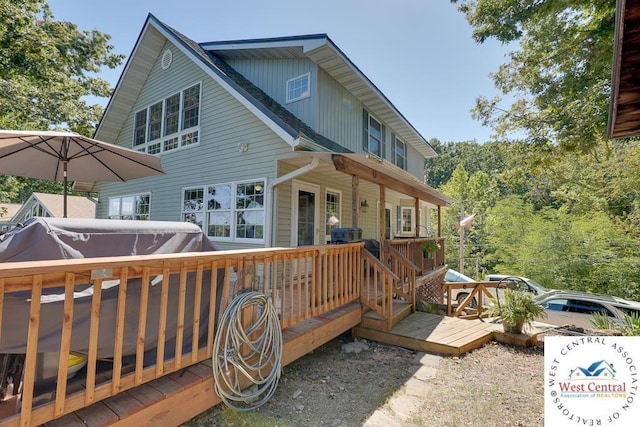 back of house featuring a wooden deck and a hot tub