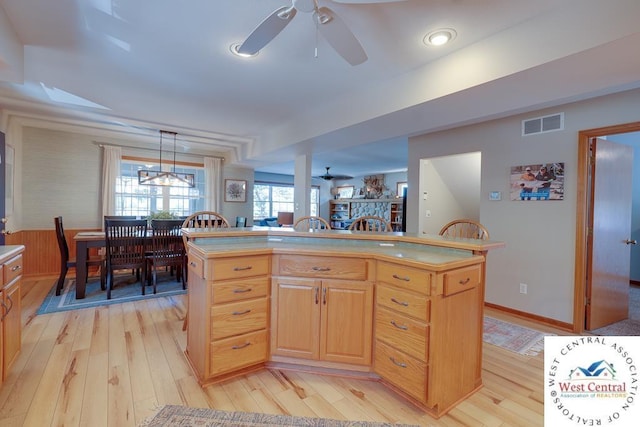 kitchen with light countertops, visible vents, light brown cabinetry, a kitchen island, and light wood-type flooring