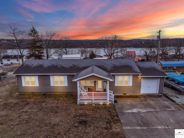 single story home featuring an attached garage, covered porch, a shingled roof, and concrete driveway