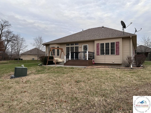 back of property featuring roof with shingles, a deck, a lawn, and a patio