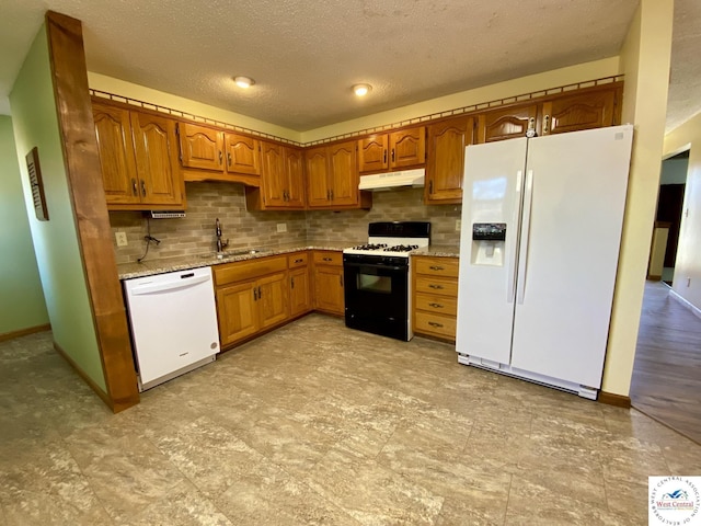 kitchen with under cabinet range hood, white appliances, a sink, brown cabinets, and tasteful backsplash