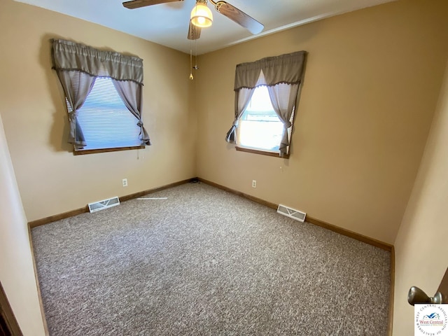 carpeted empty room with baseboards, visible vents, and ceiling fan