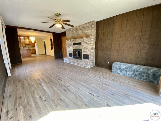 unfurnished living room with wooden walls, a ceiling fan, and wood finished floors