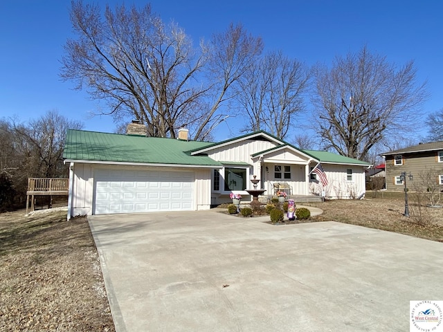 ranch-style house with concrete driveway, a chimney, metal roof, an attached garage, and board and batten siding