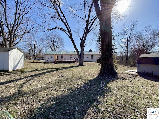 view of yard featuring an outdoor structure, a wooden deck, and a storage unit