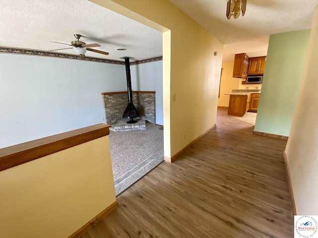 hallway with a textured ceiling, baseboards, and wood finished floors