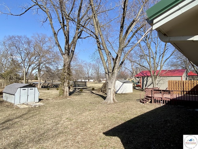 view of yard with an outdoor structure, a deck, and a shed