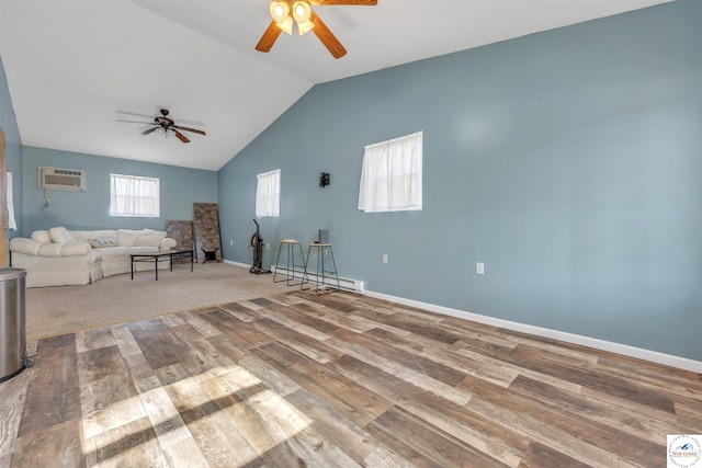 unfurnished living room with a baseboard radiator, lofted ceiling, a wall mounted AC, wood finished floors, and baseboards