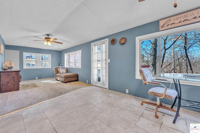 living area with tile patterned flooring, visible vents, a ceiling fan, and carpet flooring