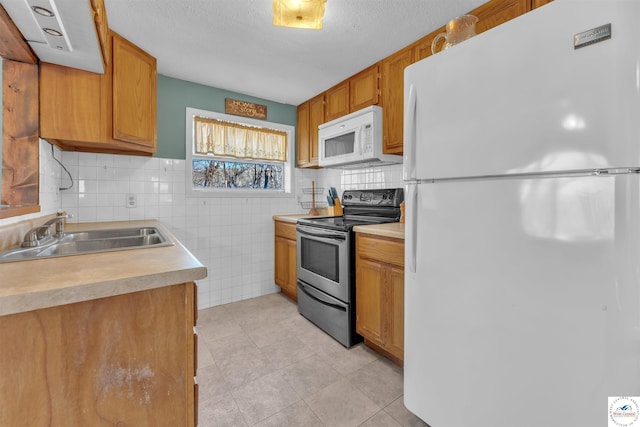 kitchen featuring light countertops, light tile patterned flooring, a sink, a textured ceiling, and white appliances