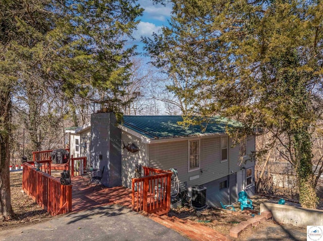 exterior space with a chimney, metal roof, central AC, and a wooden deck