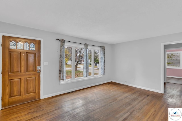 foyer entrance featuring a healthy amount of sunlight, visible vents, baseboards, and wood finished floors