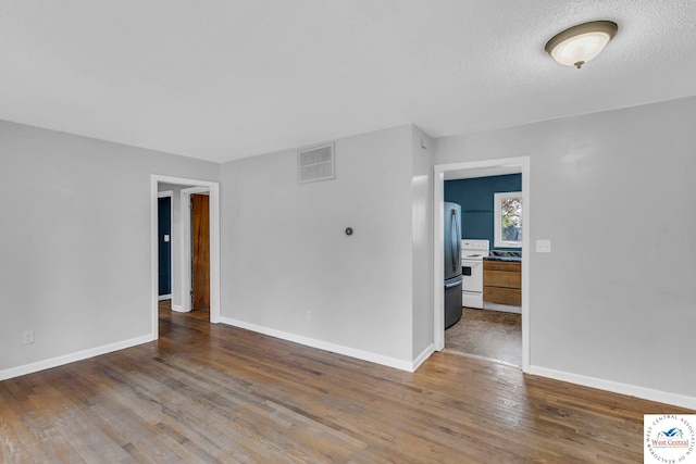 empty room with baseboards, a textured ceiling, visible vents, and wood finished floors