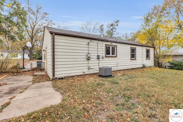 back of property with fence, cooling unit, and a yard