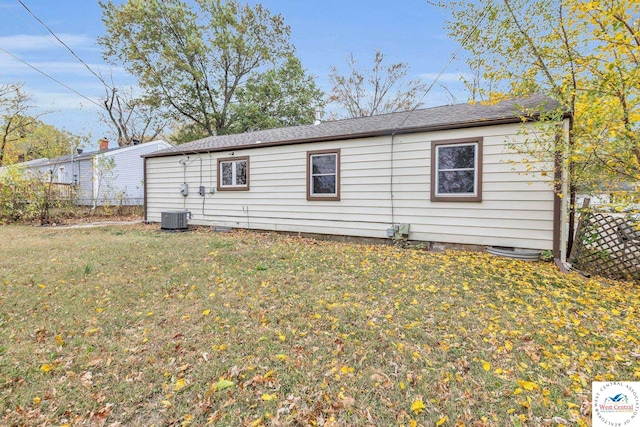 rear view of house featuring central AC, a yard, and fence