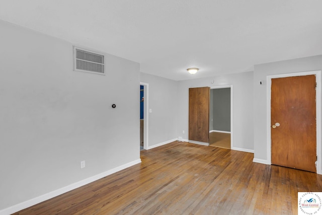 empty room with baseboards, visible vents, and wood finished floors