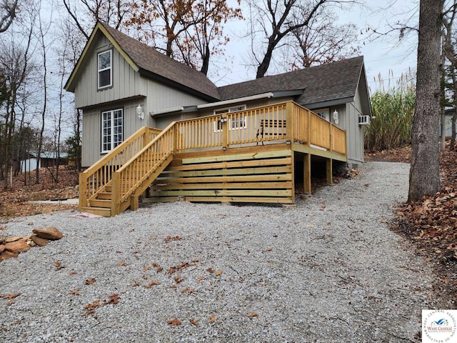 view of front of home featuring stairway, a deck, and roof with shingles