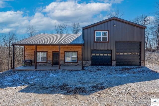 chalet / cabin featuring metal roof, covered porch, dirt driveway, and stone siding