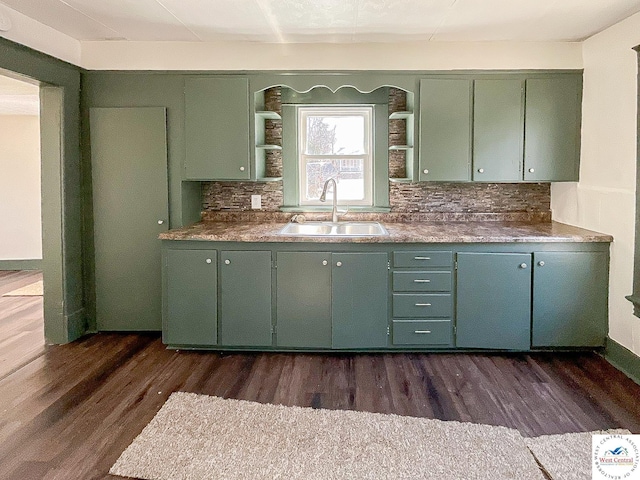 kitchen featuring tasteful backsplash, dark wood-type flooring, a sink, and green cabinetry