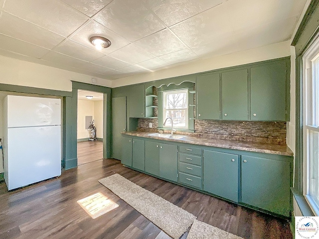 kitchen with dark wood finished floors, a sink, freestanding refrigerator, and green cabinetry