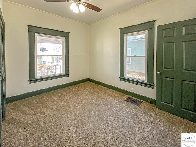 spare room featuring carpet floors, visible vents, plenty of natural light, and baseboards