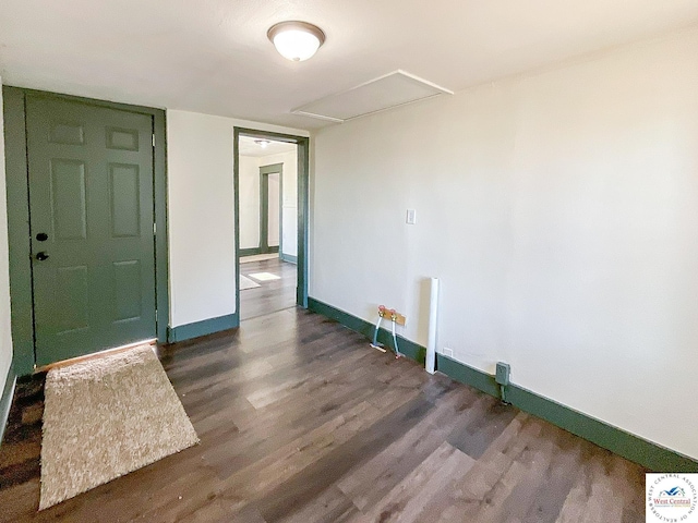 unfurnished room with attic access, baseboards, and wood finished floors