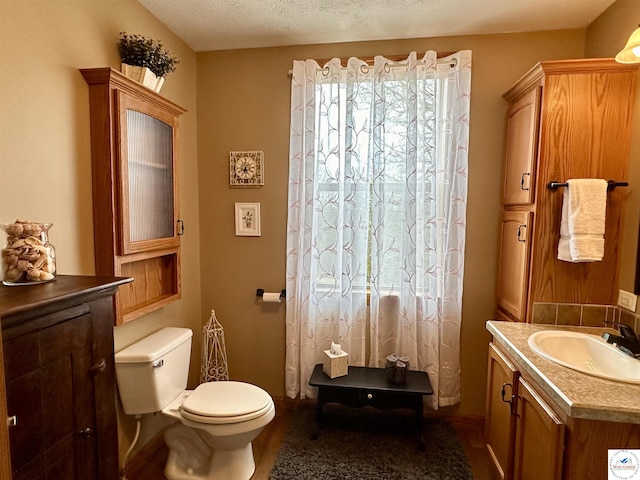 bathroom with vanity, toilet, and a textured ceiling