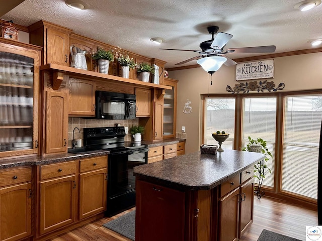 kitchen featuring crown molding, tasteful backsplash, dark countertops, wood finished floors, and black appliances