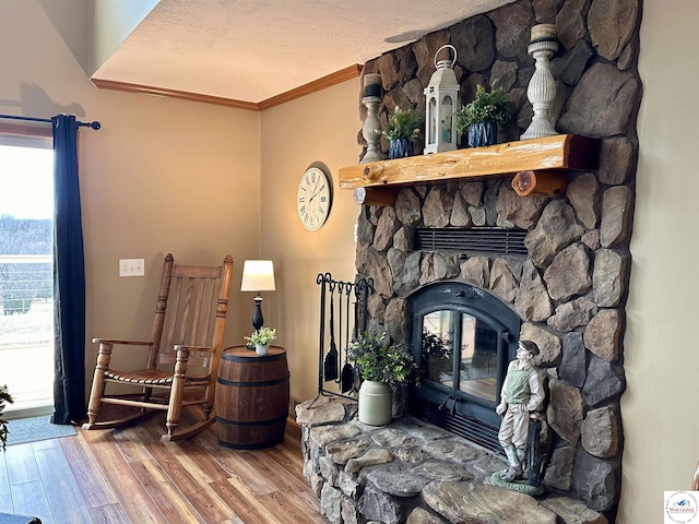 living area with a textured ceiling, ornamental molding, a fireplace, and wood finished floors