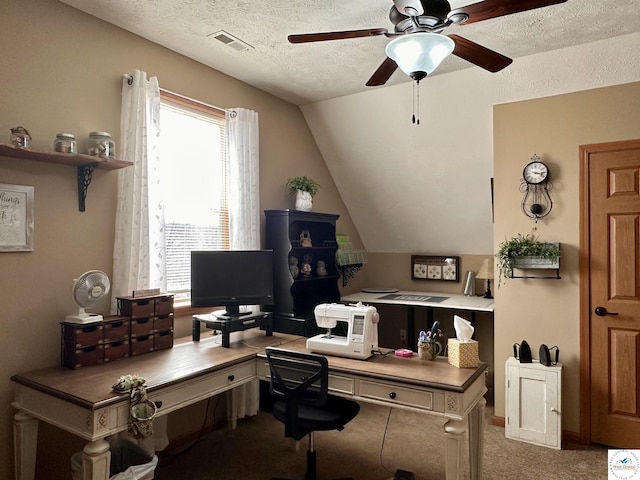 office area featuring a textured ceiling, lofted ceiling, visible vents, a ceiling fan, and carpet