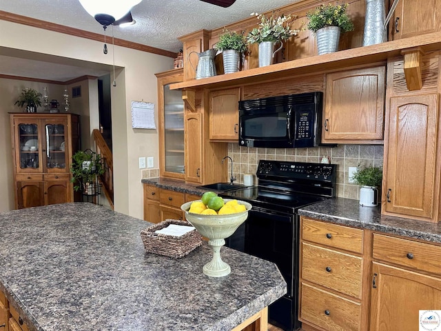 kitchen with ornamental molding, black appliances, tasteful backsplash, and a sink